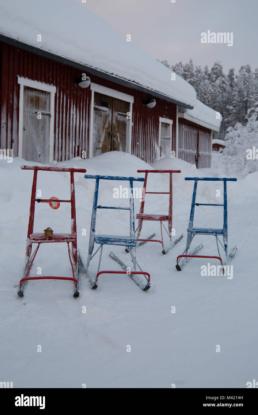 Patada multicolores trineos aparcado fuera cubierto de nieve, granero Lappeasuando, Suecia Foto de stock