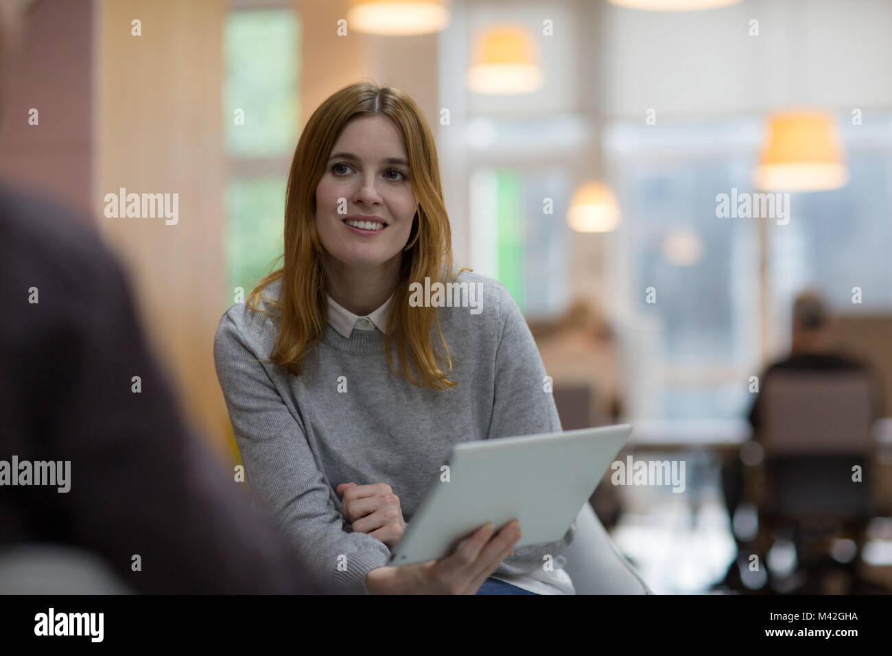 Empresaria en una reunión sosteniendo una tableta digital Foto de stock