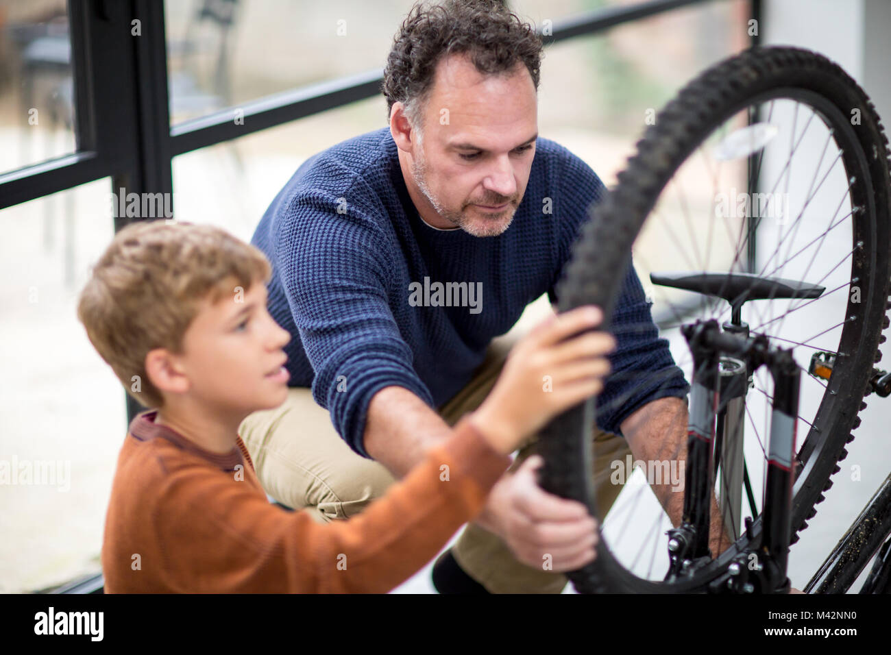 Hijo de padre enseñando cómo cuidar de su bicicleta. Foto de stock