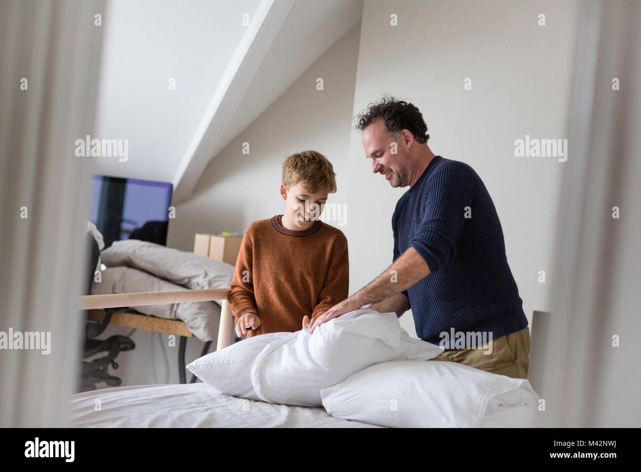 Hijo de padre enseñar cómo hacer la cama Foto de stock