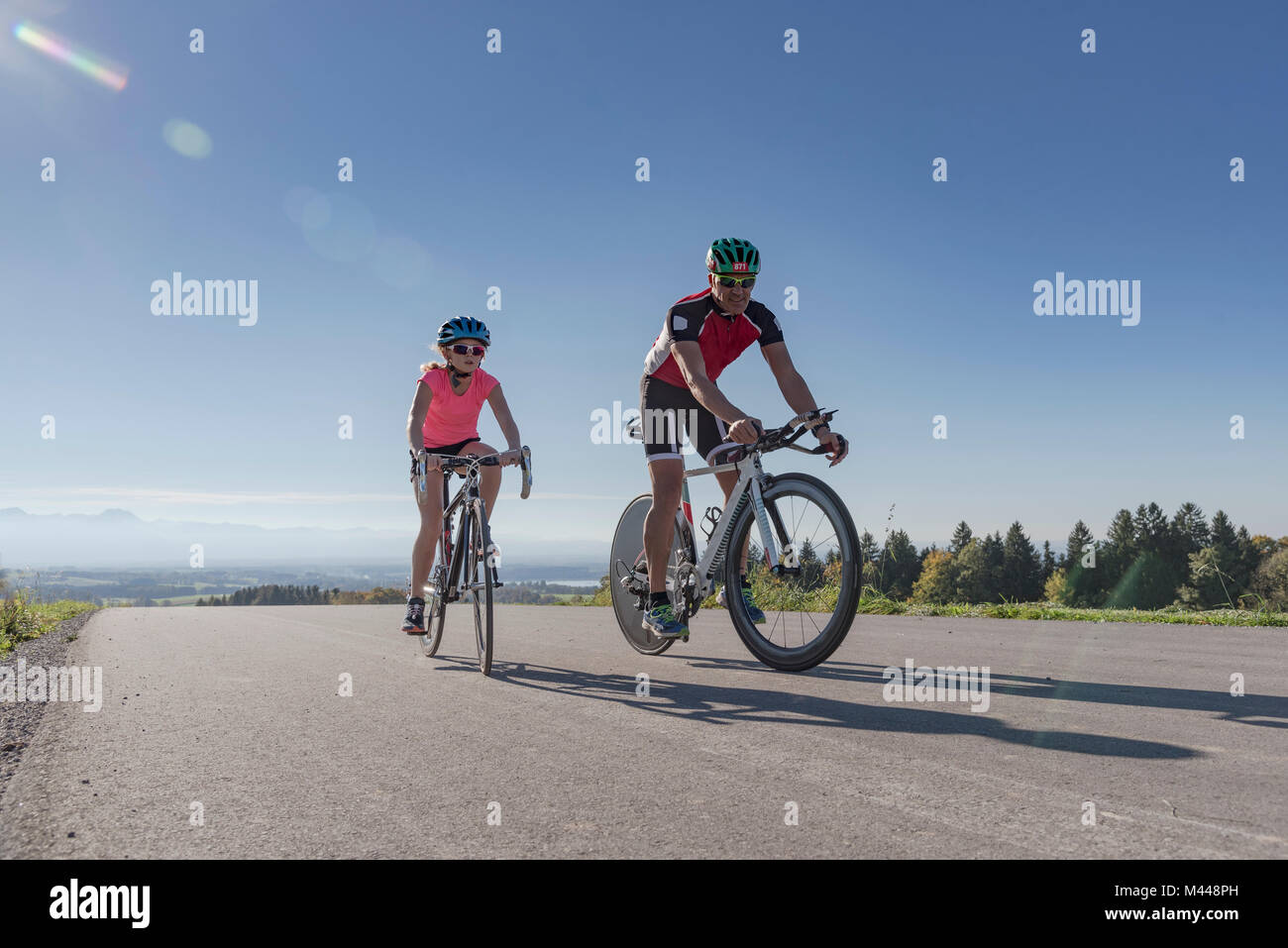 Chica y padre ciclistas ciclismo en carretera rural Foto de stock