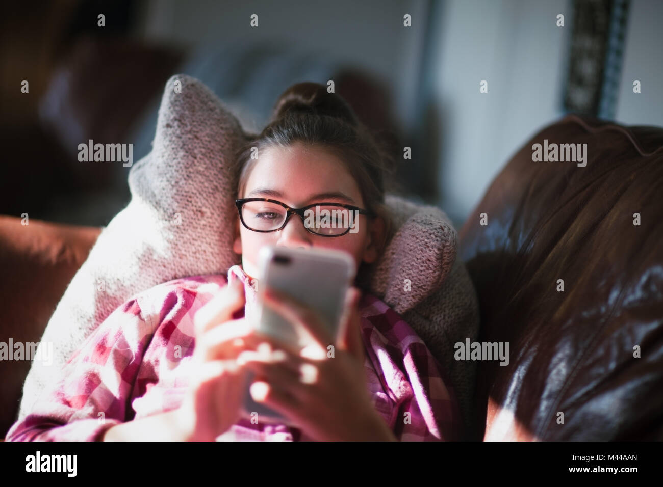 Chica relajándose en el sofá, mirando el smartphone Foto de stock