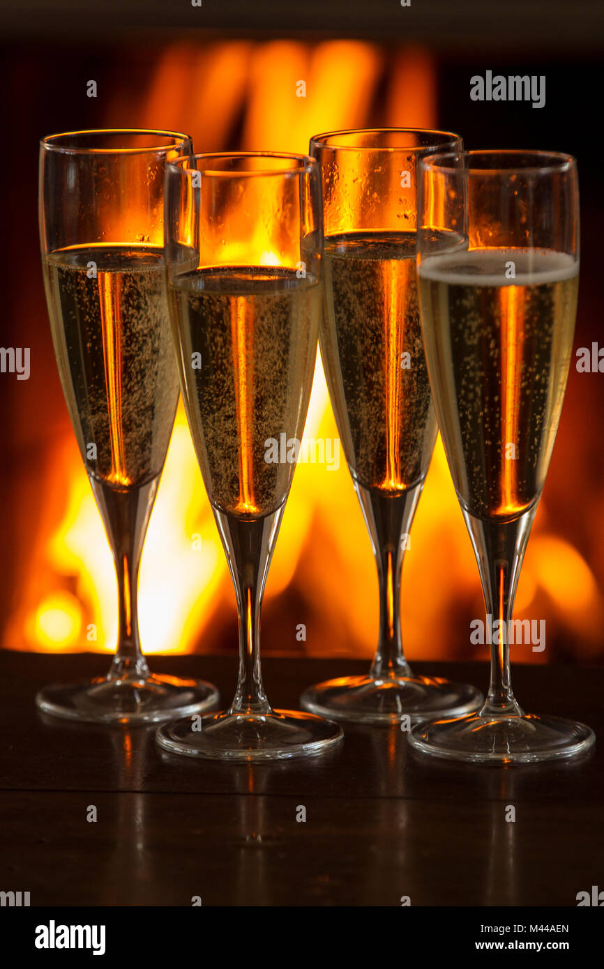 https://c8.alamy.com/compes/m44aen/cuatro-copas-de-champagne-llenas-en-la-mesa-en-frente-de-fuego-ardiente-m44aen.jpg