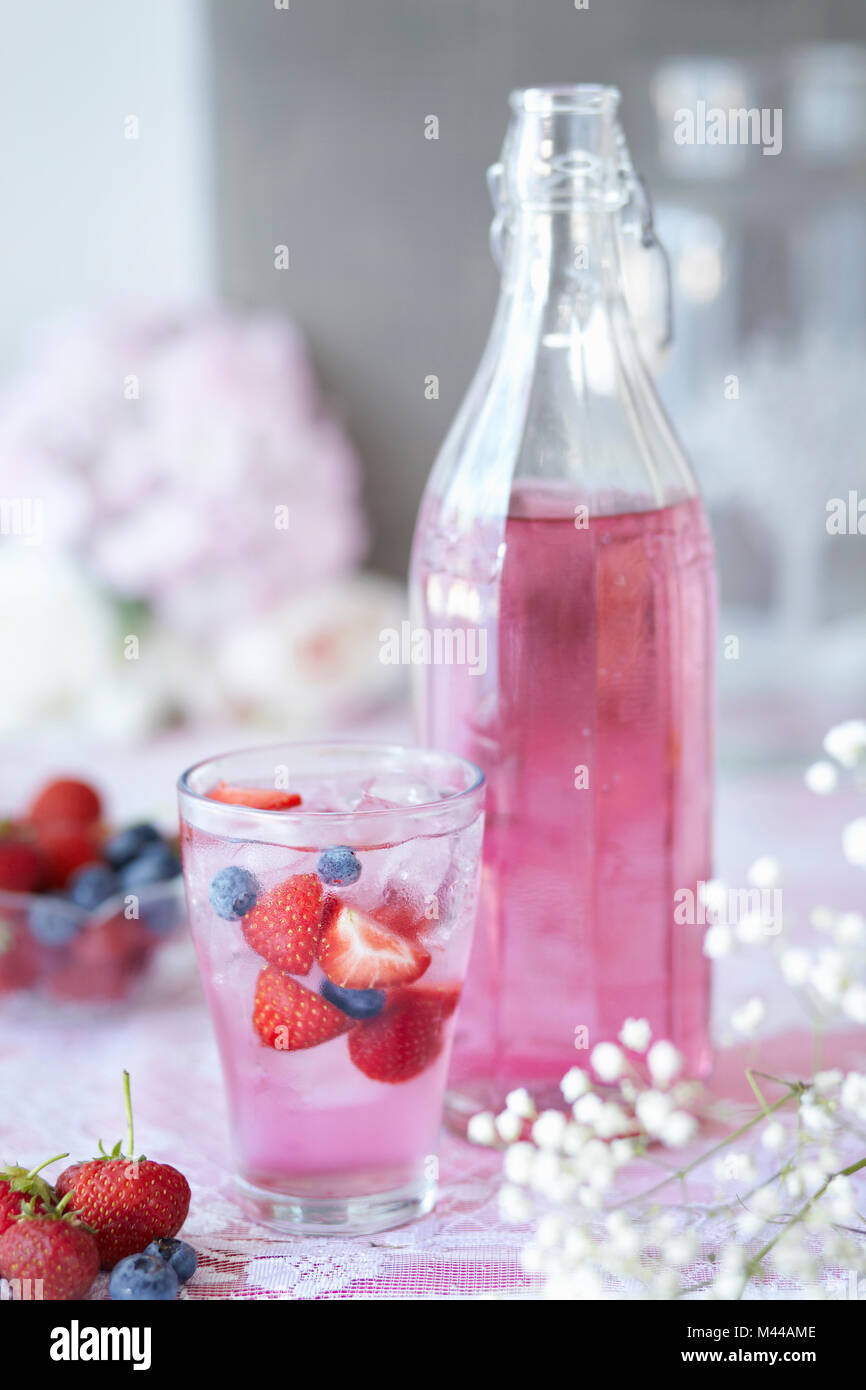 Vaso de berry cordial con fruta fresca, una botella de vidrio al lado cordial, close-up Foto de stock