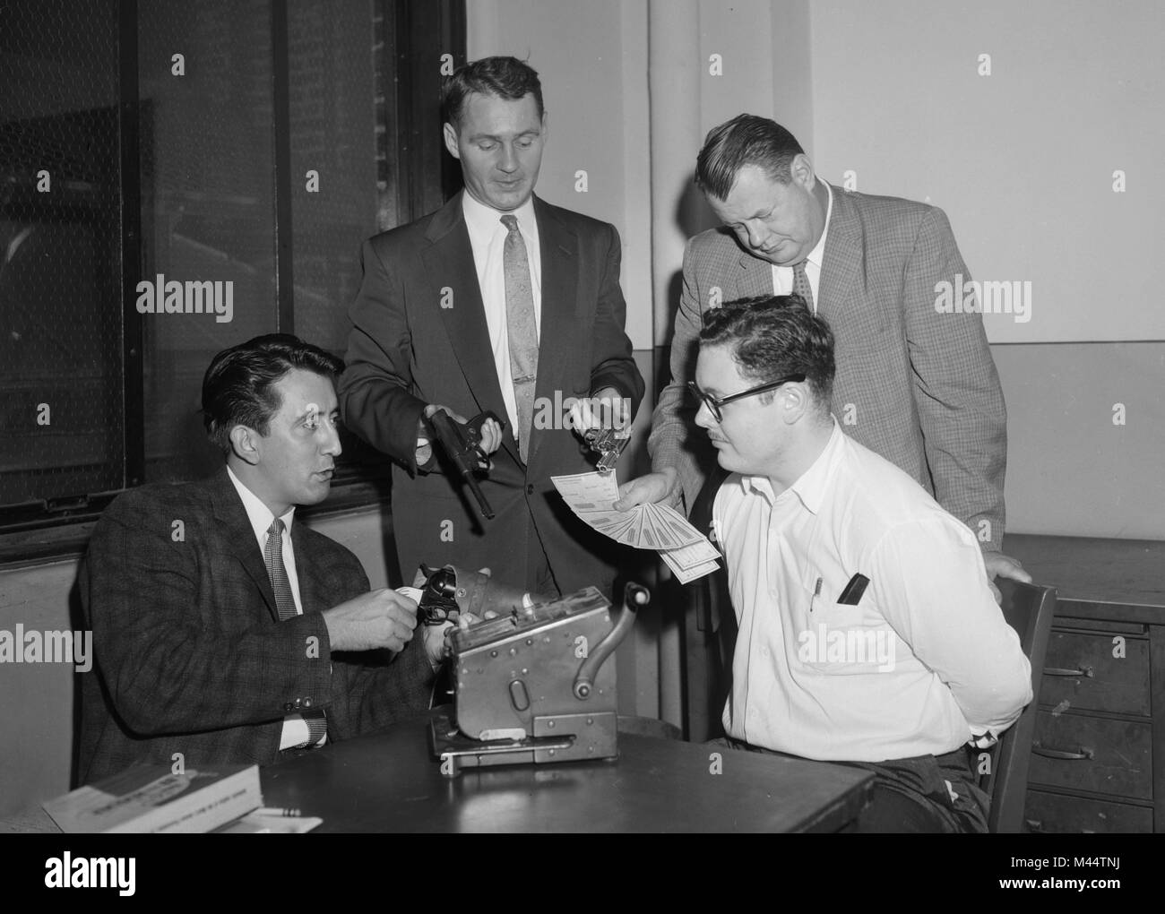 Una sospecha de Chicago Comprobar falsificador es enfrentado por varios policías con las pruebas de su delito, ca. 1950. Foto de stock