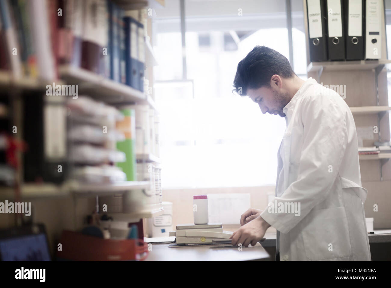 Macho joven farmacéutico vaso de píldora de pesaje básculas de farmacia  Fotografía de stock - Alamy