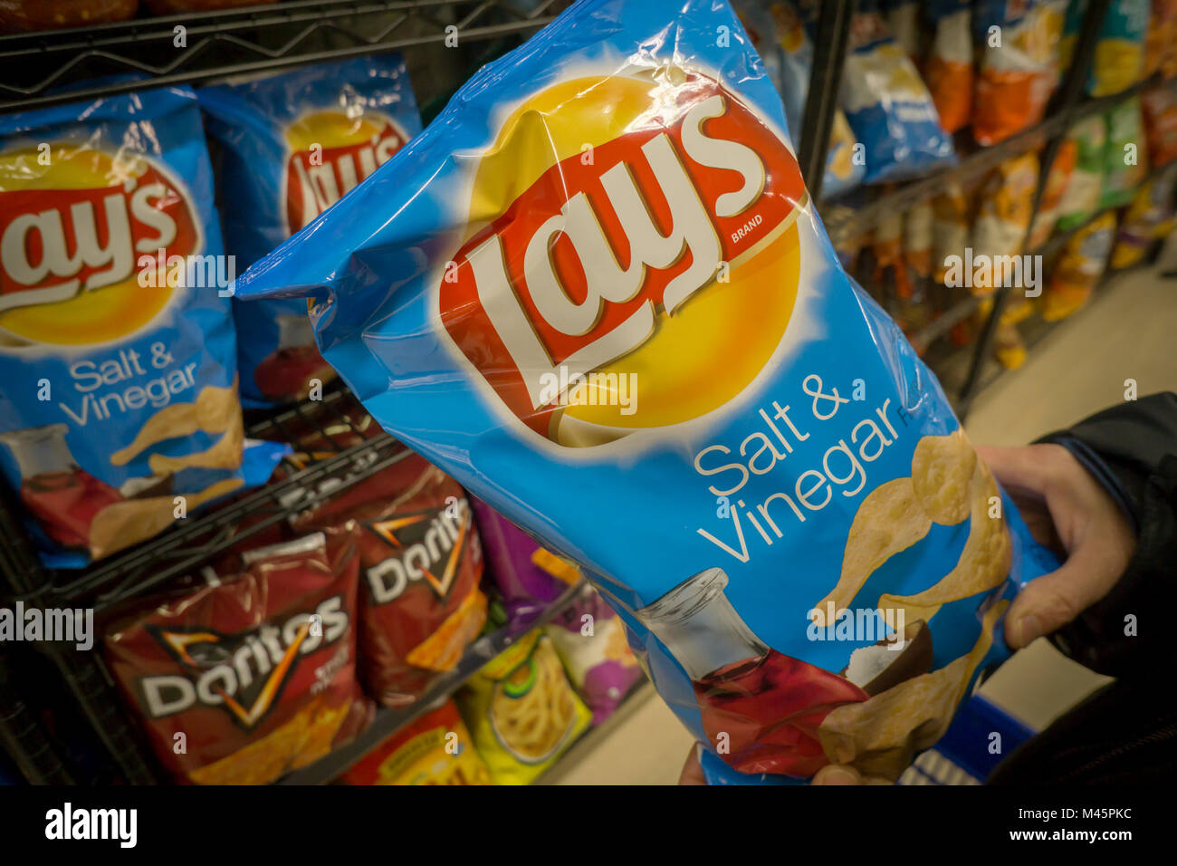 Un comprador elige una bolsa de patatas fritas marca Frito-Lay de PepsiCo  snacks en un supermercado en Nueva York el lunes, 12 de febrero de 2018.  PepsiCo está previsto liberar sus ganancias