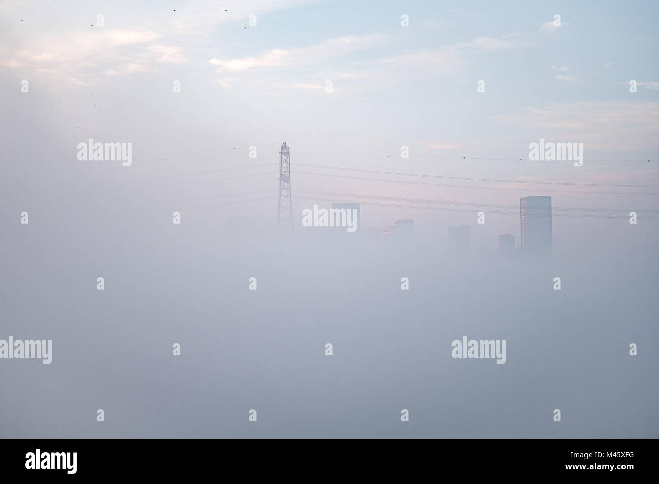 Abu Dhabi cubierto con la manta de niebla densa - ahogado en la niebla, edificios y torres eléctricas a través de niebla peaking Foto de stock