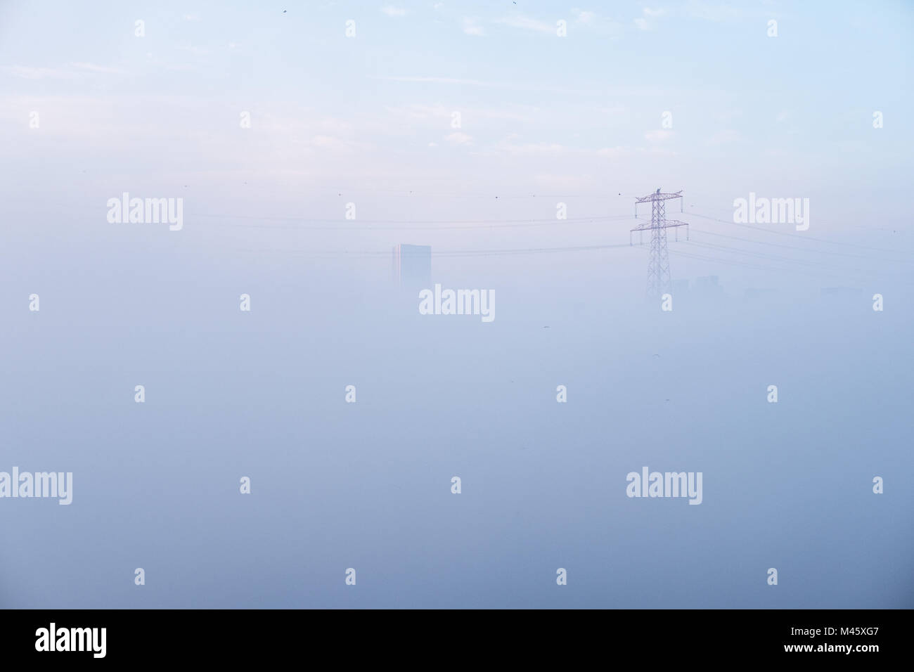 Abu Dhabi cubierto con la manta de niebla densa - ahogado en la niebla, edificios y torres eléctricas a través de niebla peaking Foto de stock
