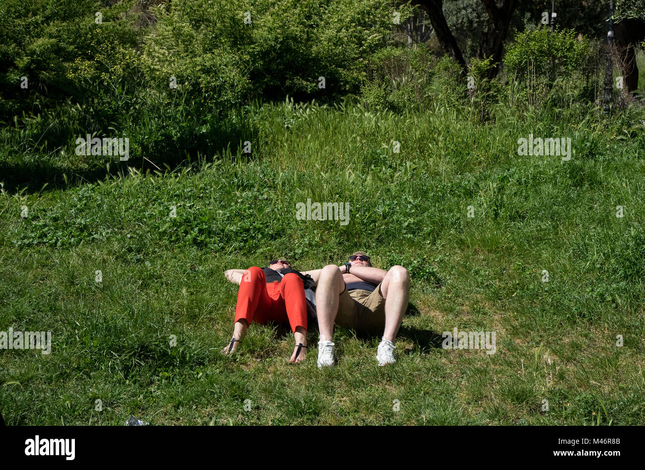 Roma, Italia: Una pareja joven descansa sobre la hierba bajo el sol Foto de stock