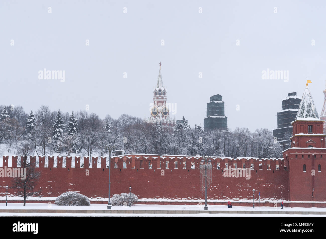 Kremlin de Moscú, la pared de ladrillo de color rojo, Spassky, Salvador, torre con campanas. Dos torres bajo cubierta de protección para trabajos de renovación. Día de invierno frío Foto de stock
