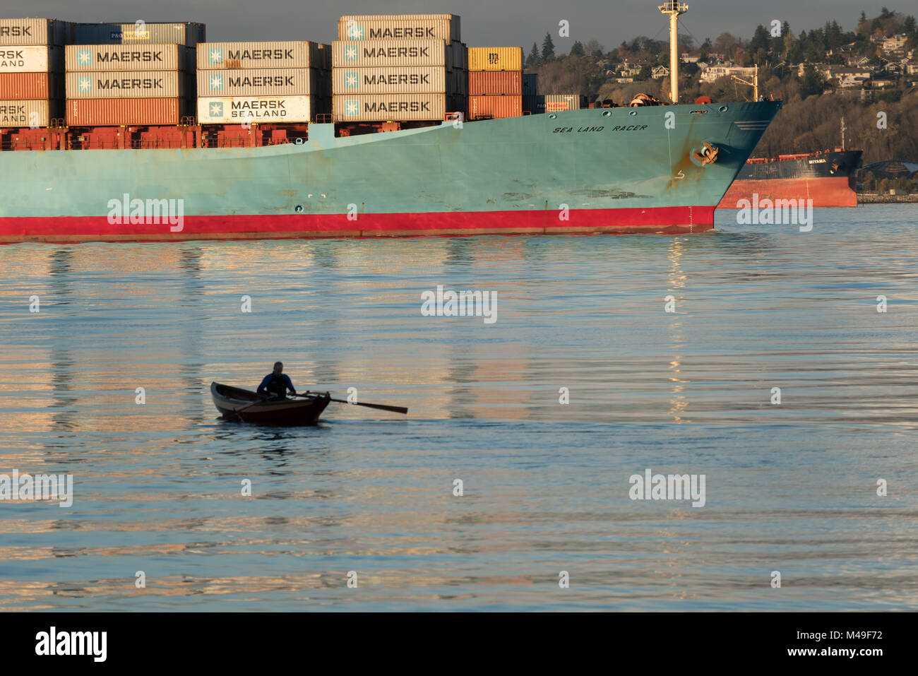 Estados Unidos, Washington, Seattle, buque portacontenedores entrando en la Bahía Elliot con una barca de remos en el primer plano. Foto de stock