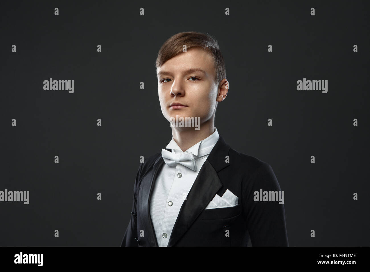 Adolescente en traje sobre un fondo negro Foto de stock