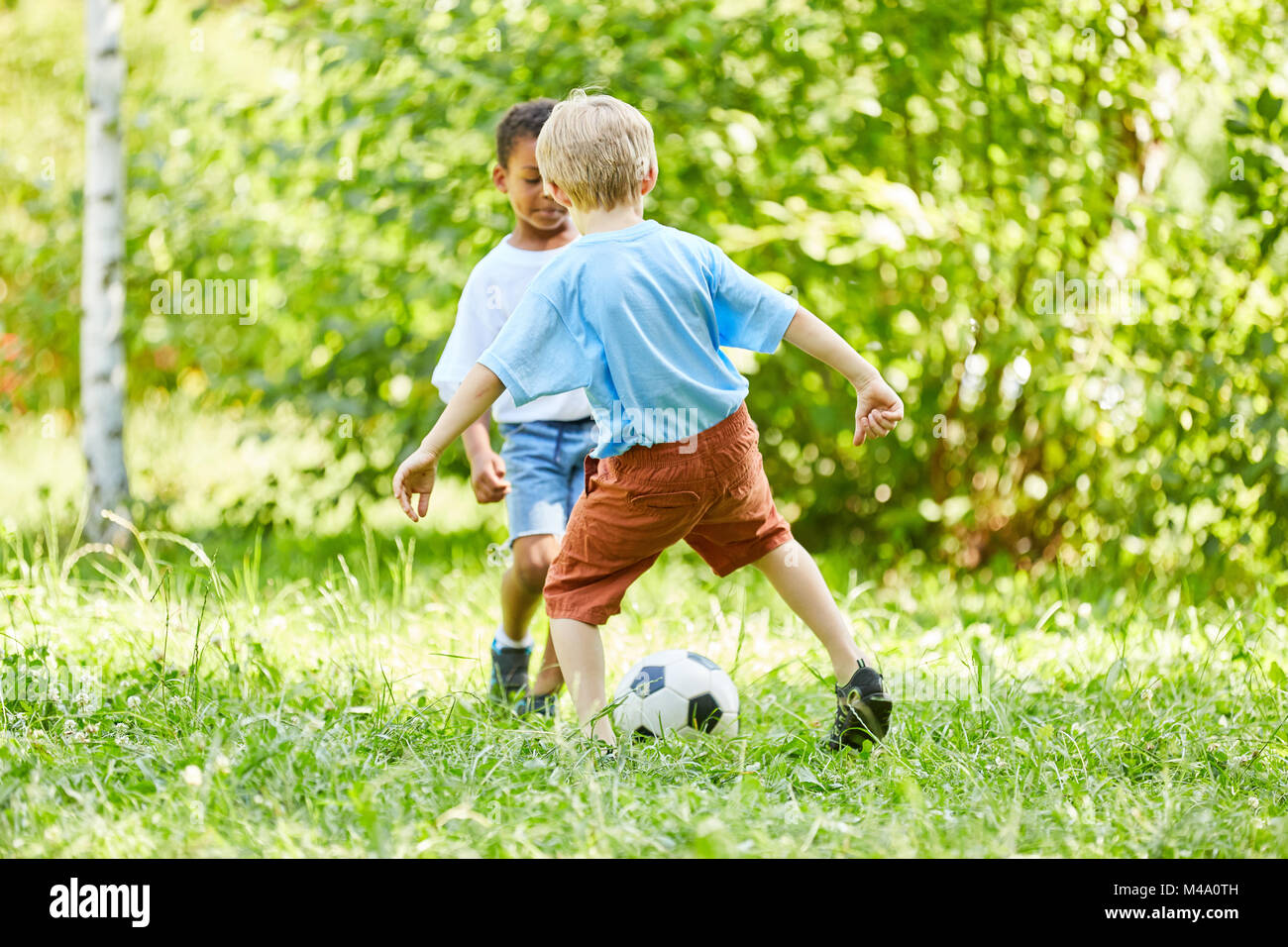 Dos niños en duelo mientras jugaba al fútbol en el club deportivo en el parque Foto de stock