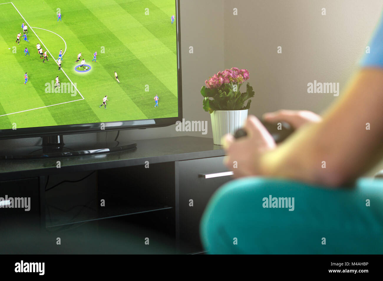 El hombre imaginario jugando fútbol o consola de juego de fútbol en la televisión en casa. Celebración gamepad en la mano. Freetime divertida actividad. Foto de stock