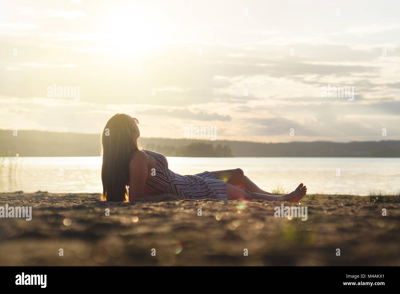 Mujer relajarse y fijar en el atardecer en la playa. Estilo de vida feliz y despreocupada. Foto de stock