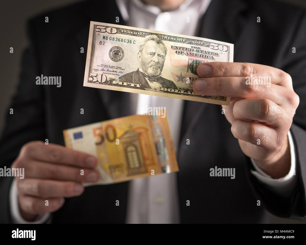 Dolar vs euro. Hombre de negocios en traje celebración 50 y Bill billetes en moneda en la mano. Tasa de cambio, la economía mundial y el concepto financiero. Foto de stock