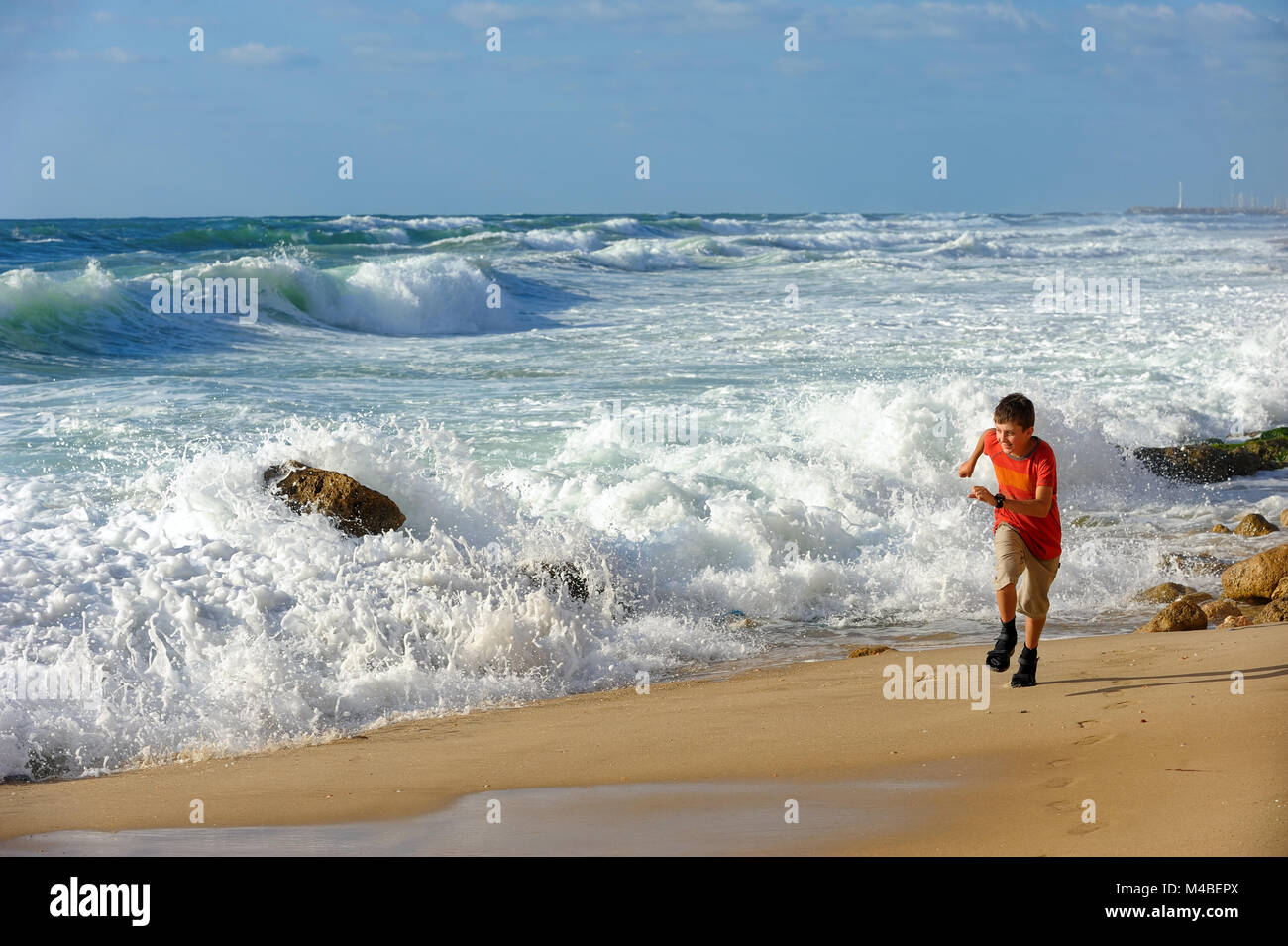 Chico corre a lo largo de la orilla del mar Foto de stock