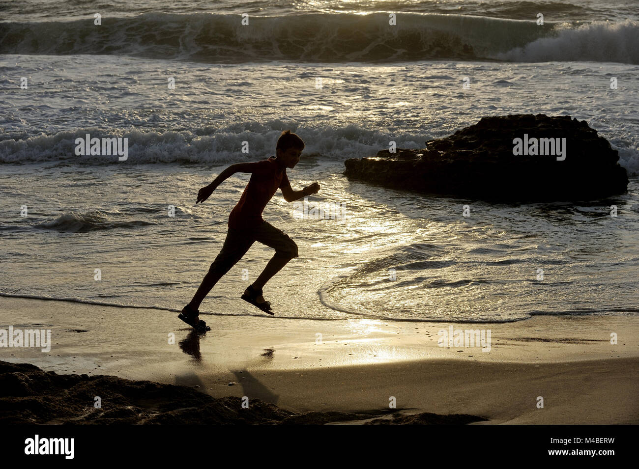 Chico corre a lo largo de la orilla del mar Foto de stock