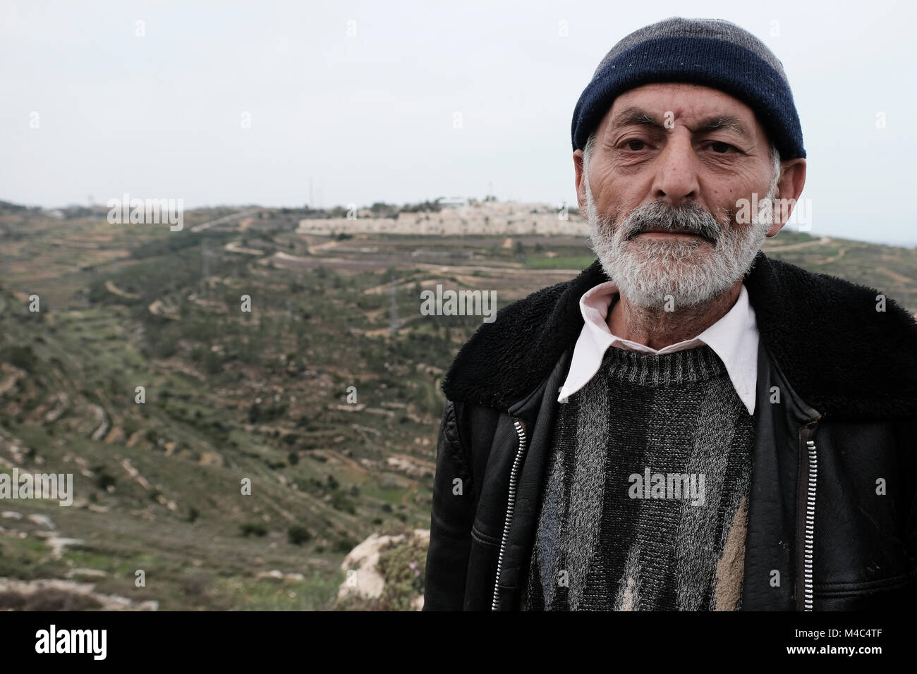 Nativ Ha'avot, Israel.15 Feb, 2018. Hacendado palestino que reclamar la devolución de sus tierras tomadas por colonos judíos posando junto a Rosh Tzurim asentamiento judío como miembros de Paz Ahora protestar junto a la avanzadilla de Nativ judíos ilegales Ha'avot el siguiente gobierno israelí intenta posponer la eliminación de algunas de las casas en el puesto a pesar de la decisión de la Corte Suprema después de aceptar la petición de un grupo de palestinos que sostuvieron las casas habían sido parcialmente construida ilegalmente en sus tierras. Crédito: Eddie Gerald/Alamy Live News Foto de stock