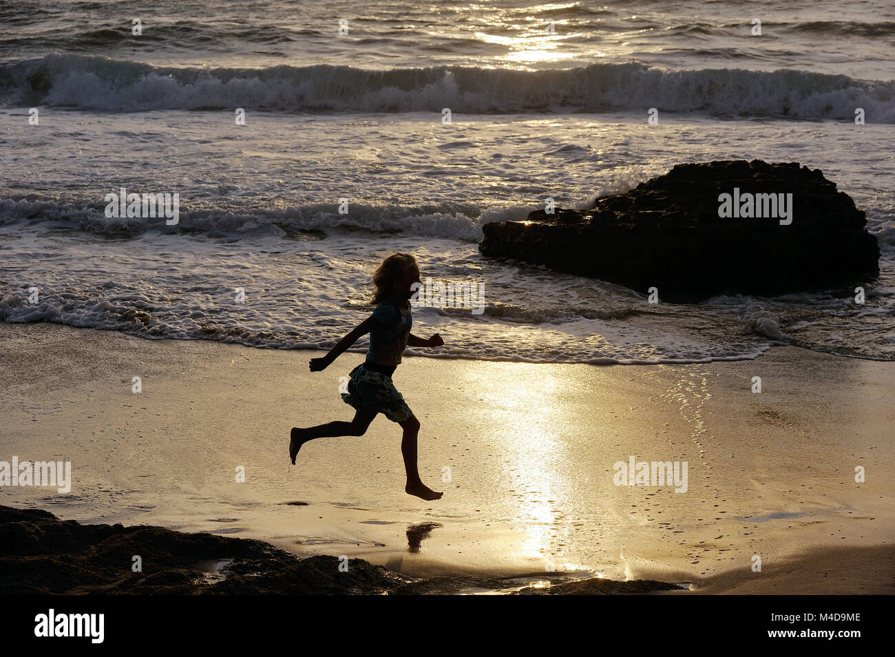 Niña corre por la orilla del mar Foto de stock