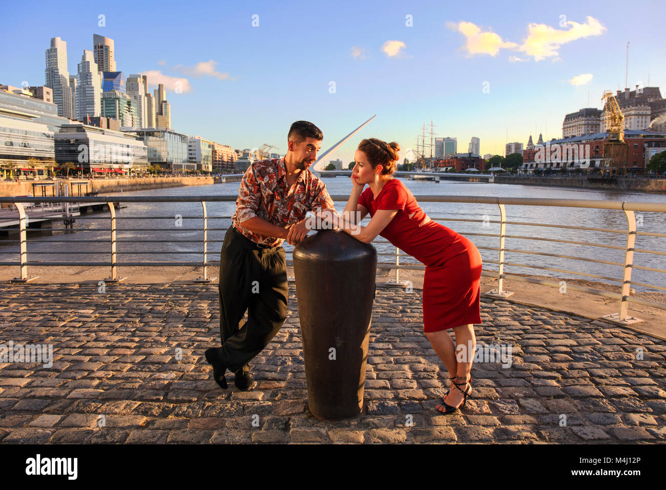 Una joven pareja en Puerto Madero, al atardecer, con el "Puente de la Mujer' en el fondo. Buenos Aires, Argentina. Foto de stock