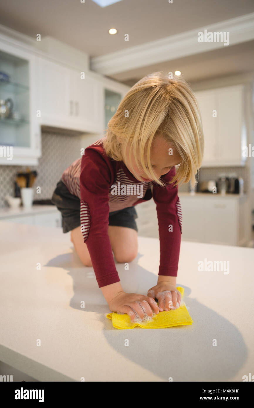 Boy Cleaning encimera de cocina con un trapo Foto de stock