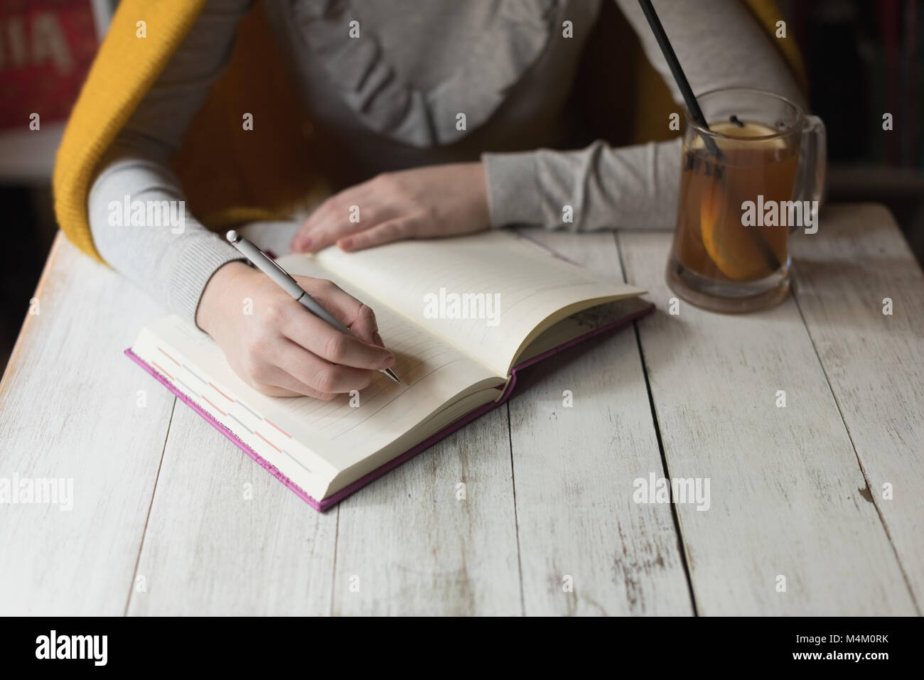 Mujer escrito nota sobre Libro con zumo de limón en la mesa Foto de stock