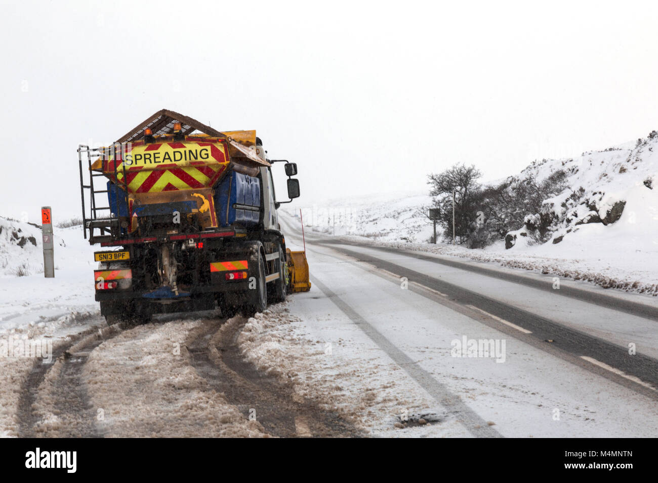 Una sal extendiendo o gritting camión al lado de un raod con Dustin g de nieve fresca en Glencoe, Escocia durante el invierno. Foto de stock