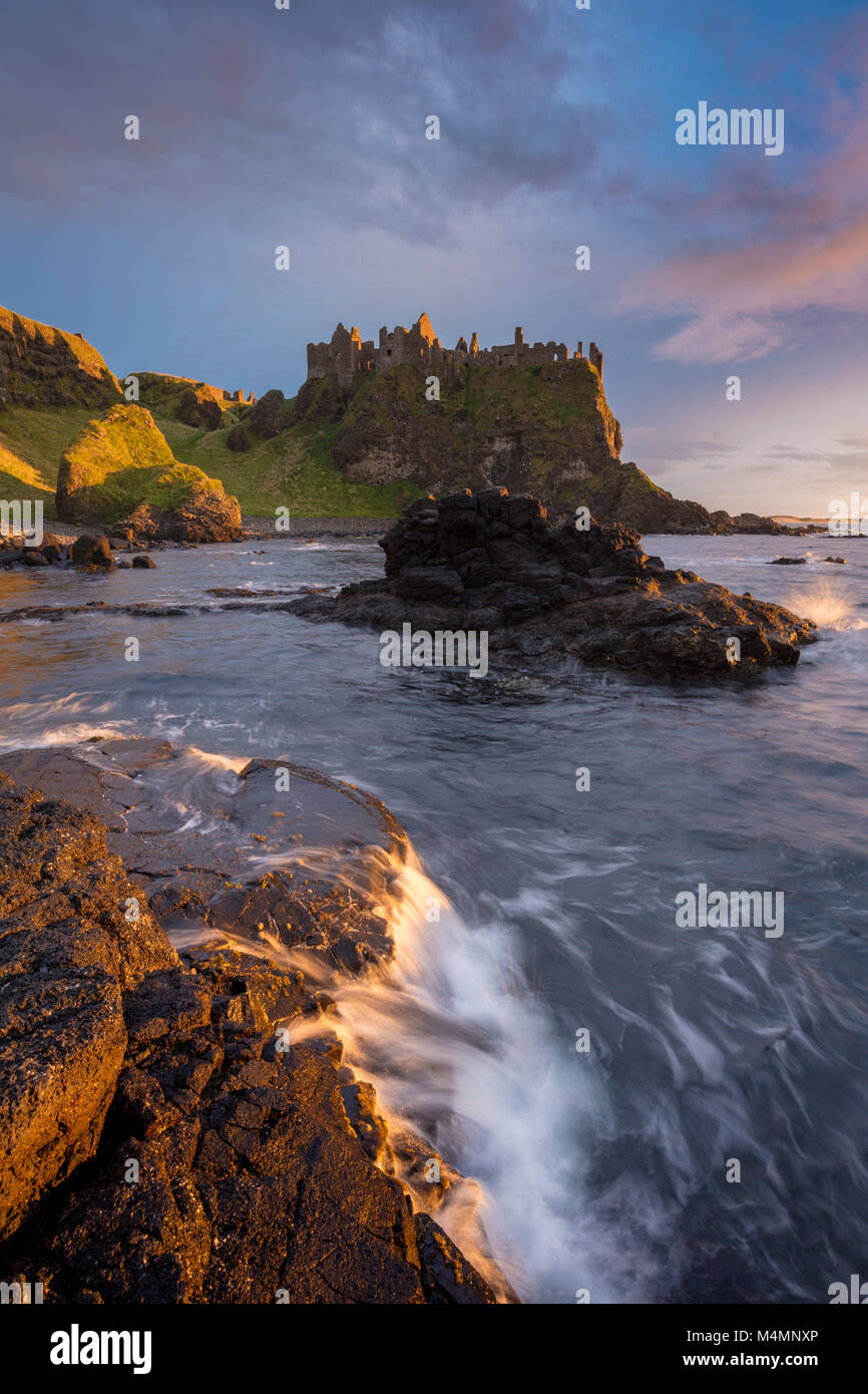 Sunset costeras debajo del Castillo de Dunluce, Condado de Antrim, Irlanda del Norte. Foto de stock