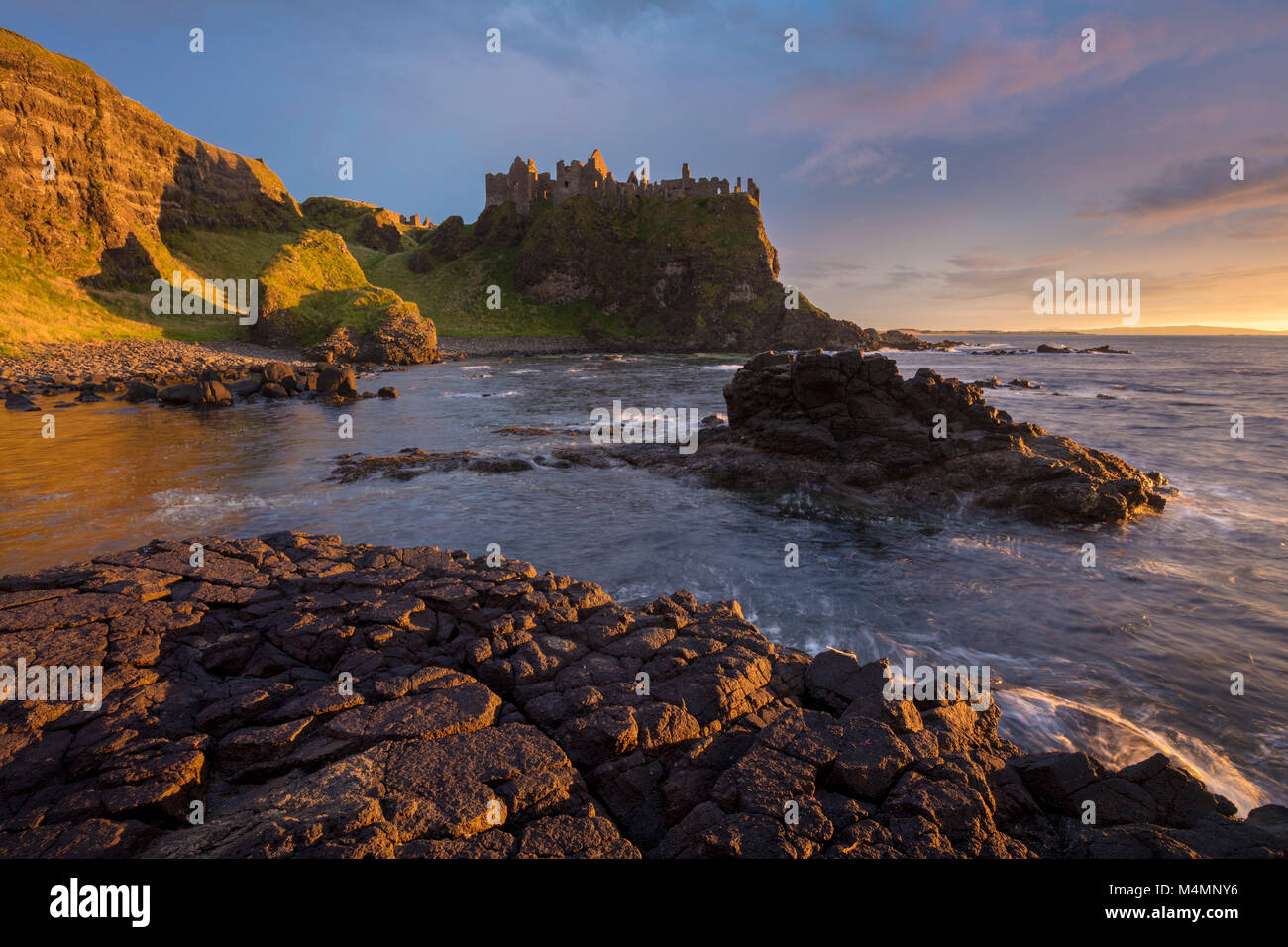 Sunset costeras debajo del Castillo de Dunluce, Condado de Antrim, Irlanda del Norte. Foto de stock