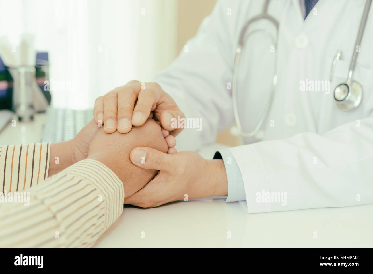 Hombre simpático médico manos sosteniendo la mano del paciente sentado al escritorio de aliento, de empatía, vítores y apoyo al examen médico. Malo nuevo Foto de stock
