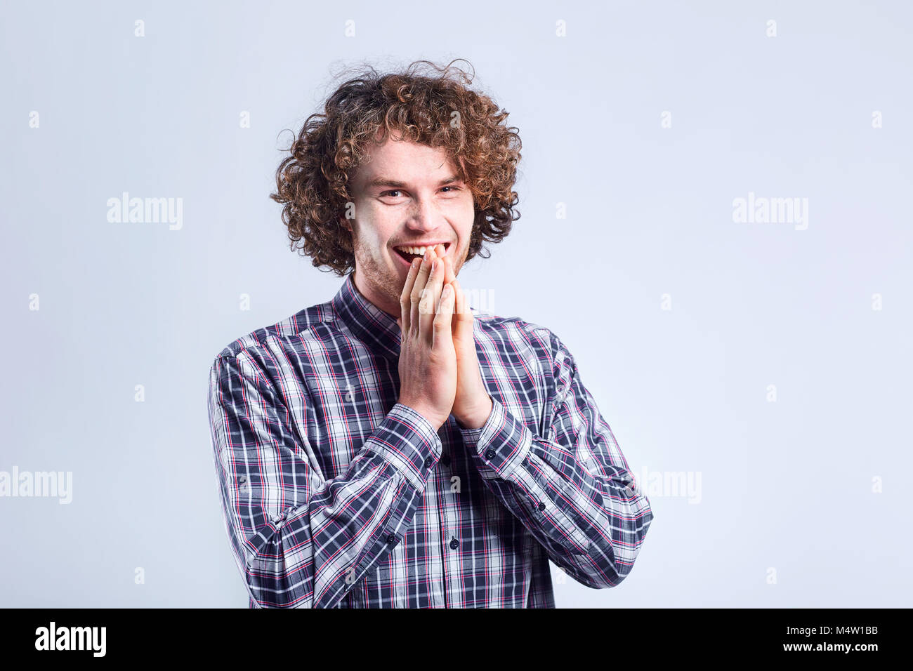 Curly-haired guy sorprendido se regocija con una emoción positiva. Foto de stock