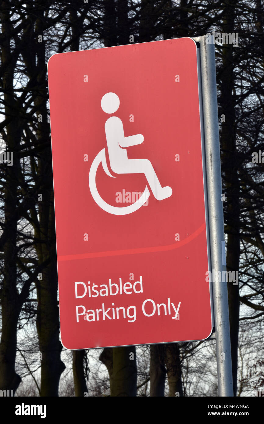 Una roja y muy perceptible conspicuo único signo de estacionamiento de discapacitados en un gran supermercado o hipermercado car park. Espacios para aparcar un coche o vehículo Foto de stock