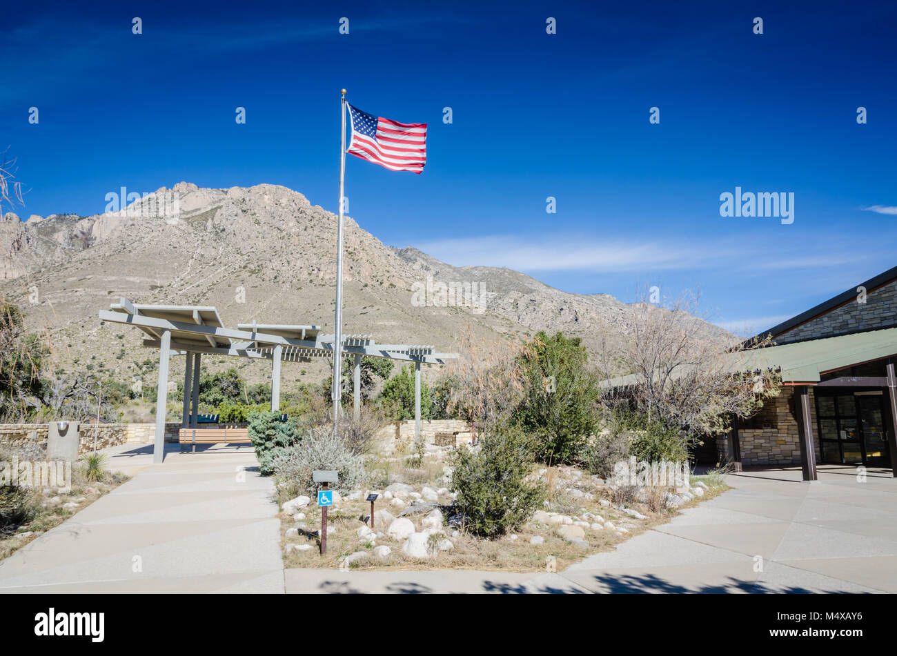 Ondear la bandera en el aire delante de montañas de Guadalupe en el Centro de Visitantes, la primera parada en el Parque Nacional de las montañas de Guadalupe para información sobre hikin Foto de stock
