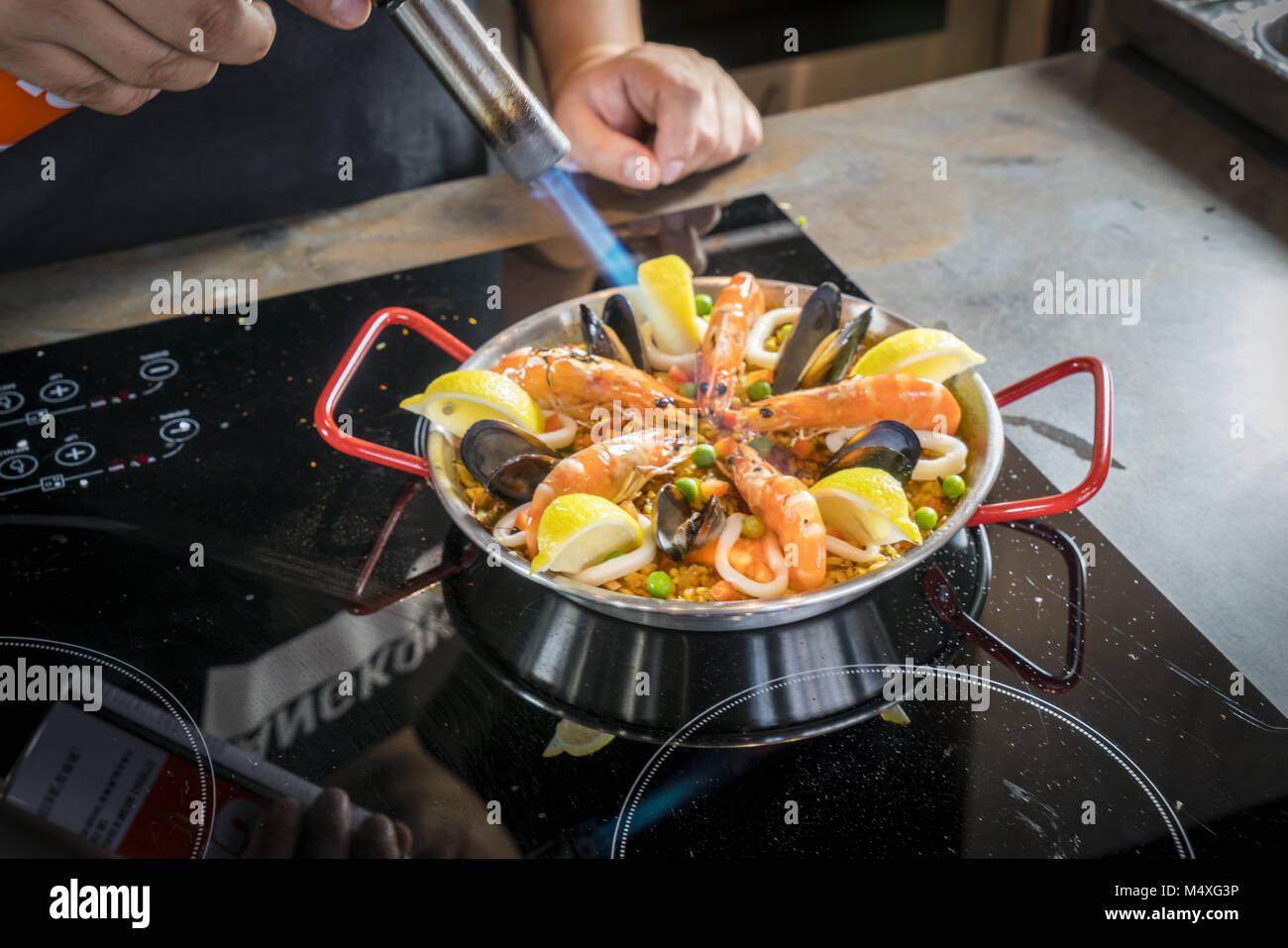 El chef es de fritura de paella de mariscos con quemador Foto de stock
