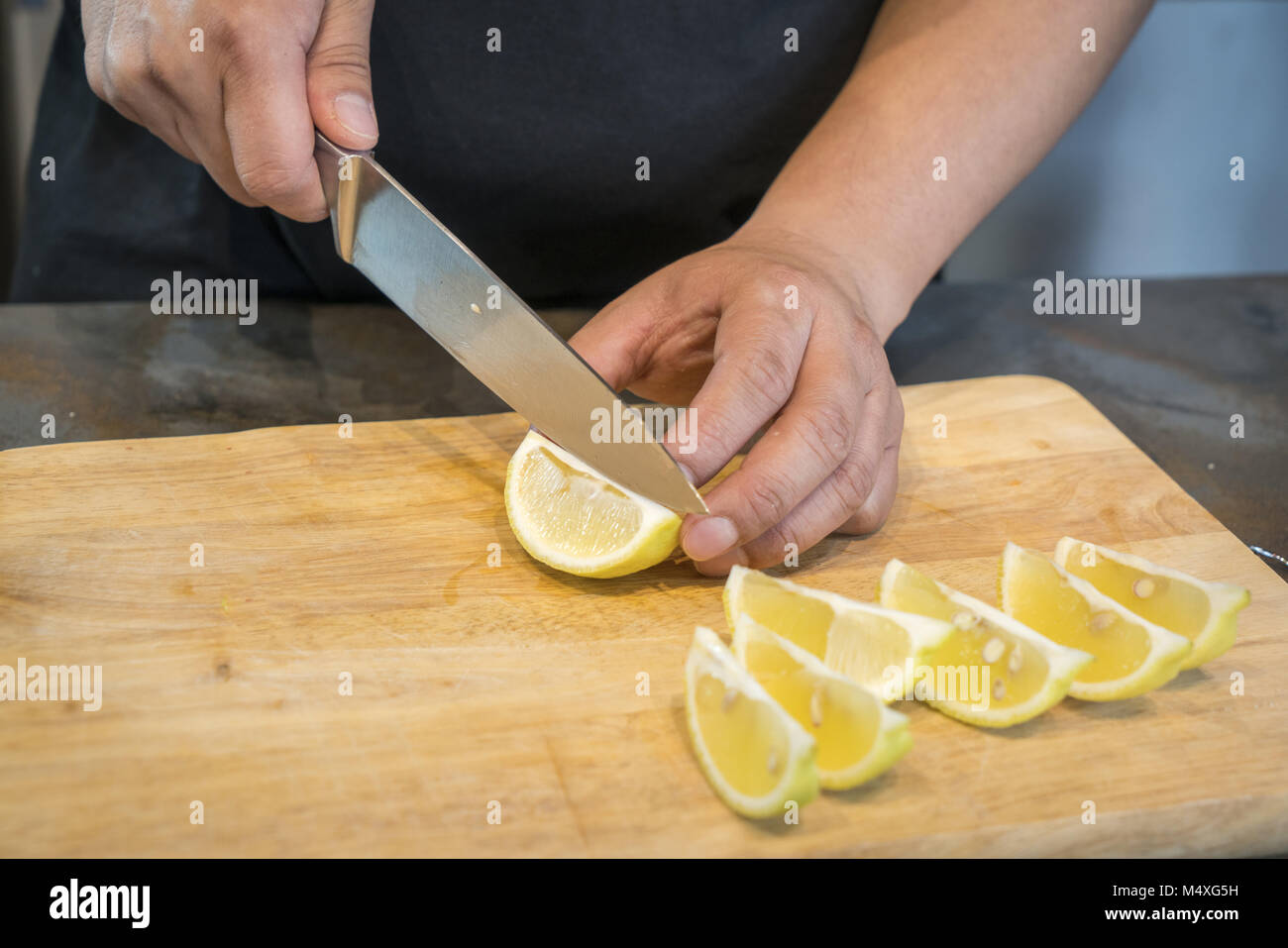 Chef slicing limón sobre la tabla de cortar de madera Foto de stock