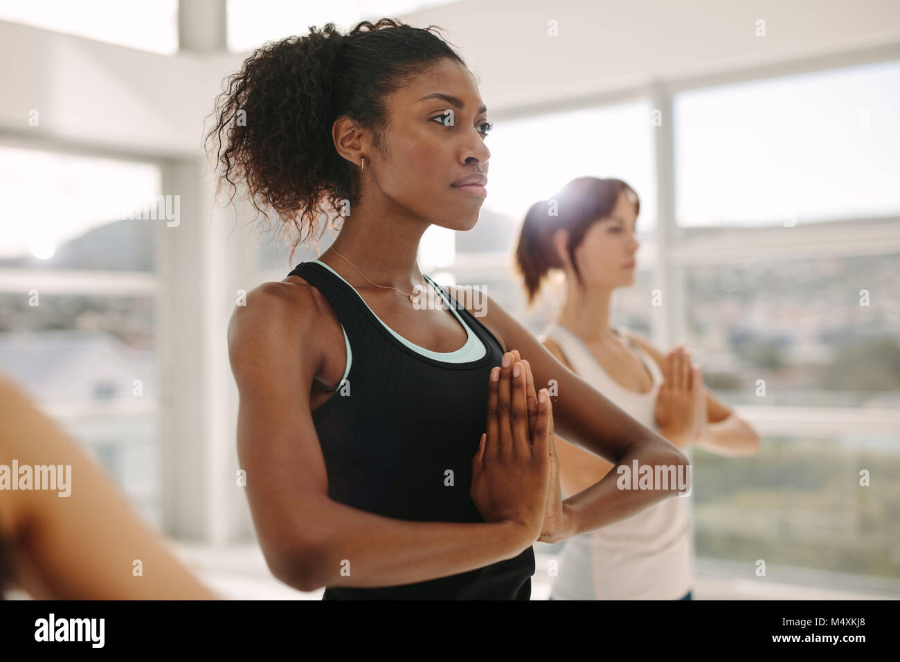 Las mujeres practicar yoga juntos, de pie con las manos en gesto Namaste. Mujer de pie en pose de yoga en el gimnasio. Foto de stock