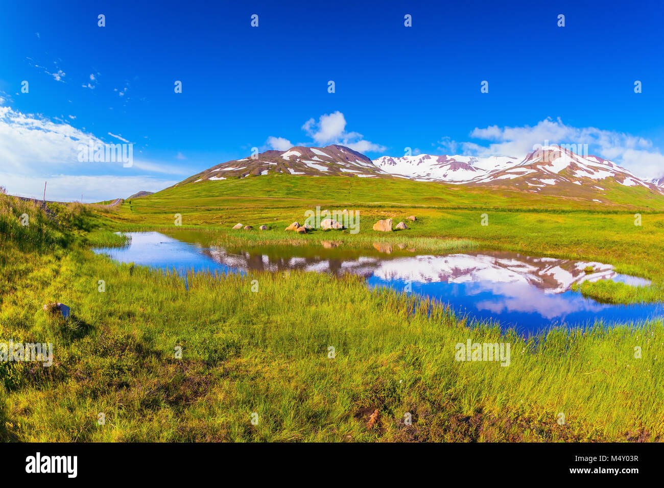 El agua del lago azul refleja las colinas nevadas en Islandia Foto de stock