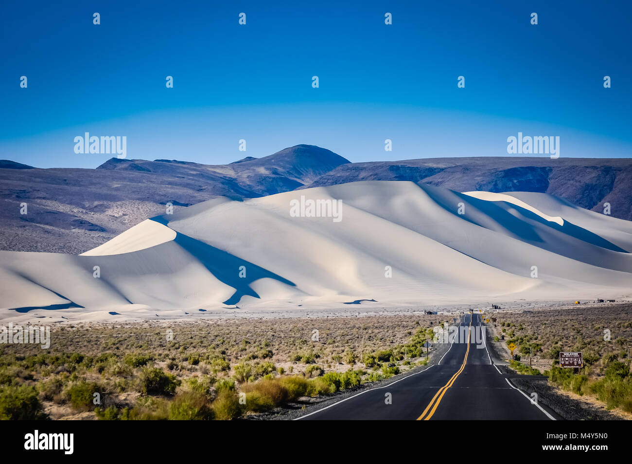 Autopista del desierto provocando enormes dunas de arena blanca en California. Foto de stock
