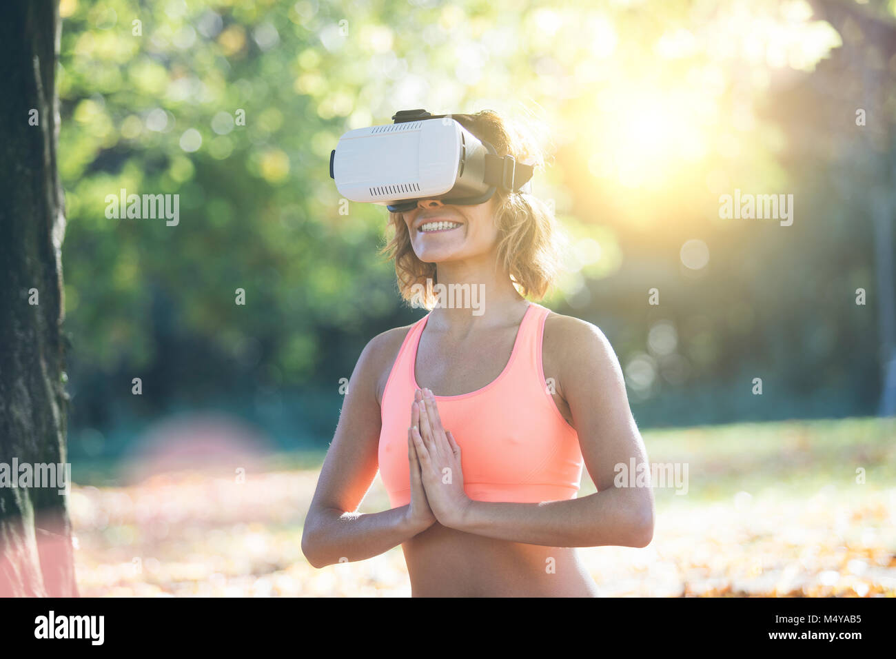 Mujer joven practicando yoga en la naturaleza con casco de RV Foto de stock