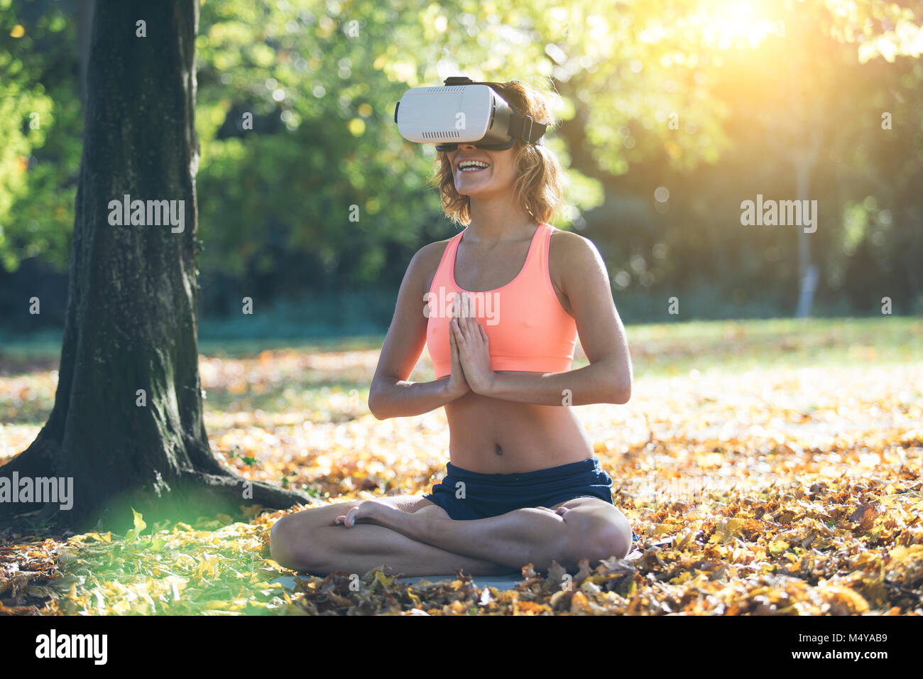Mujer joven practicando yoga en la naturaleza con casco de RV Foto de stock