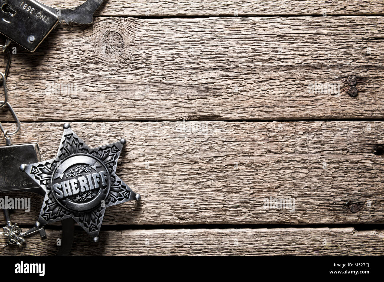 Estrella de Sheriff y esposas en mesa de madera Foto de stock
