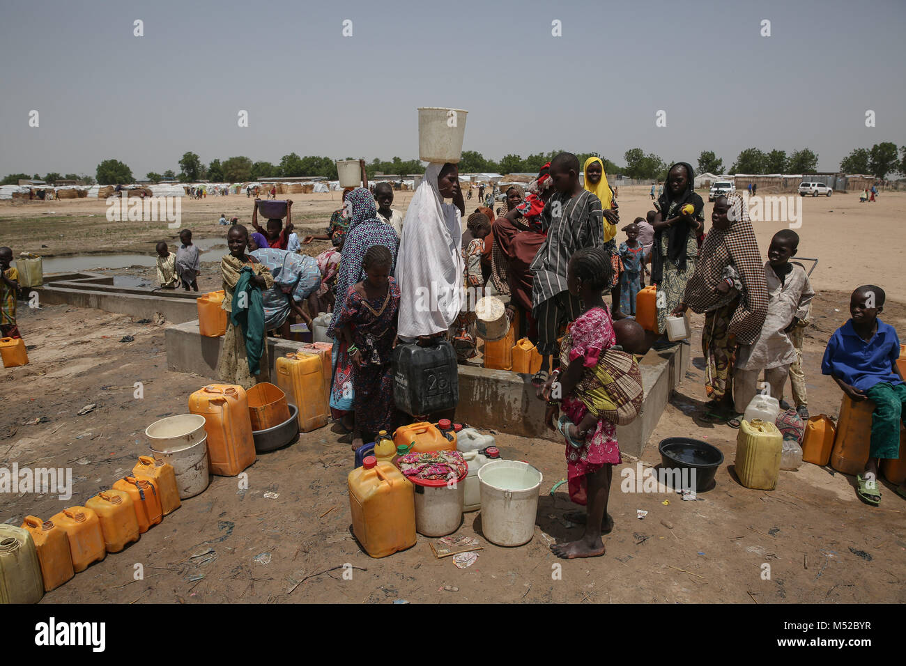 Las personas desplazadas se reúnen para recoger agua en un campamento de desplazados internos en las afueras de Maiduguri. Foto de stock