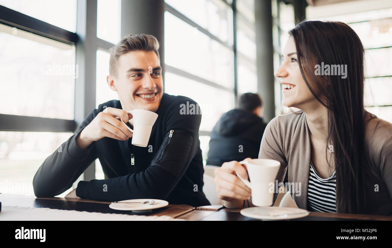 Alegre pareja disfrutando de un café juntos en la moderna cafetería.beber cafeína bebidas calientes sobre una ruptura con business partner.Amigo reunión de café Foto de stock