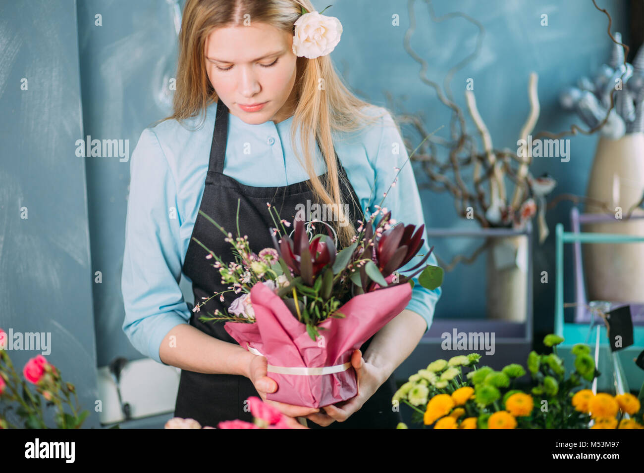 Jóvenes displasing floristería flores sobre fondo azul. Foto de stock