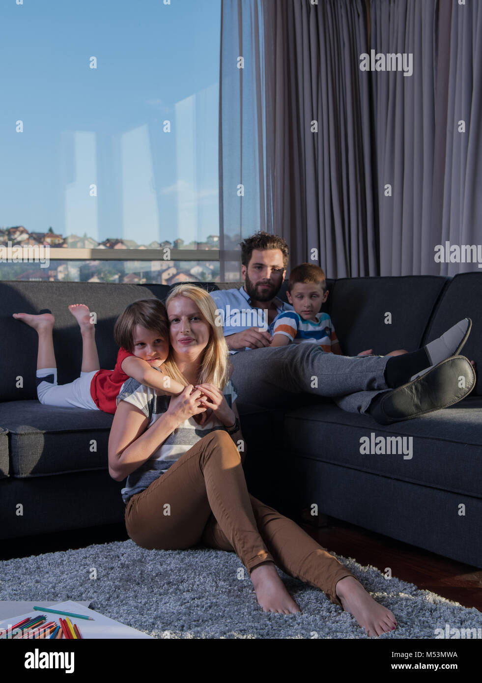 Una joven familia feliz jugando juntos en la casa en el suelo usando un ...
