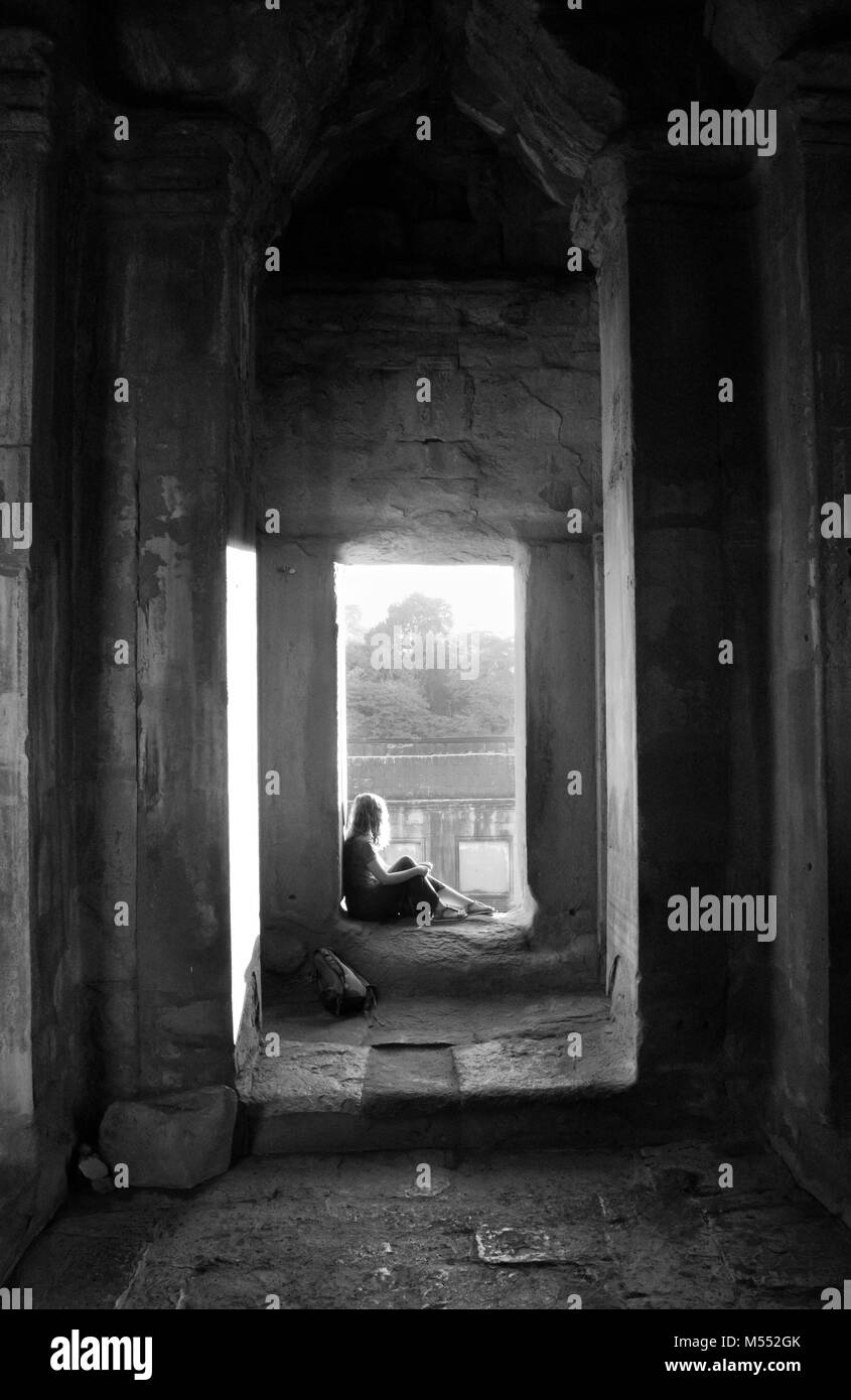 Las hembras jóvenes sentados en la entrada al templo de Angkor Wat, la luz del sol brillante. Foto de stock