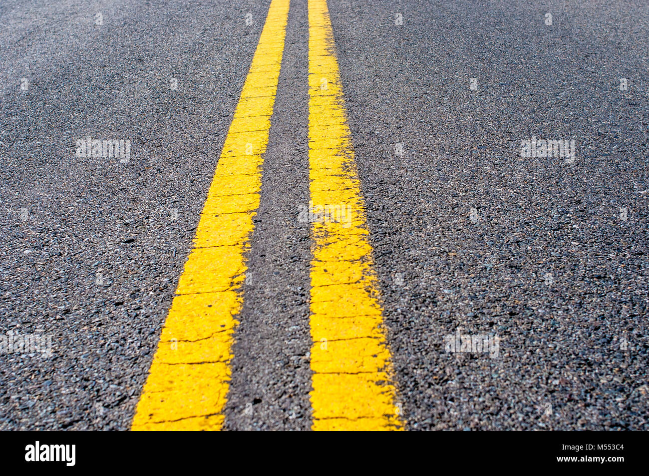 Línea divisoria doble amarillo sobre negro asfalto de carretera Foto de stock