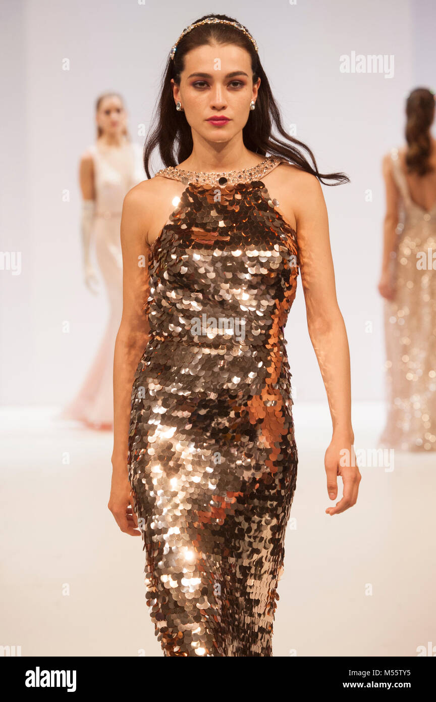 Modelo de pasarela de moda vestidos de noche vestidos de oro durante el  womenswear moda en moda. El comercio Fashion show corrió 18º-20º de febrero  de 2018 en el NEC, Birmingham, Reino